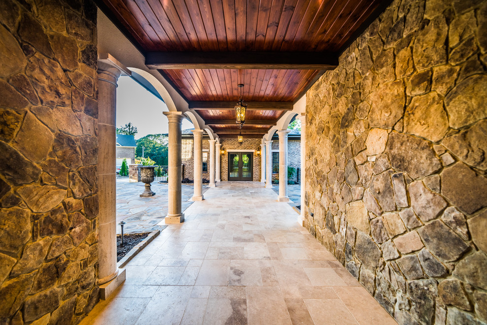 Mid-sized mountain style travertine floor and beige floor foyer photo with brown walls and a glass front door