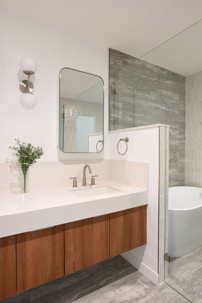 Mid-sized modern wet room bathroom in Austin with flat-panel cabinets, medium wood cabinets, a freestanding tub, multi-coloured tile, porcelain tile, porcelain floors, an undermount sink, engineered quartz benchtops, grey floor, a hinged shower door, white benchtops, a shower seat, a double vanity and a floating vanity.