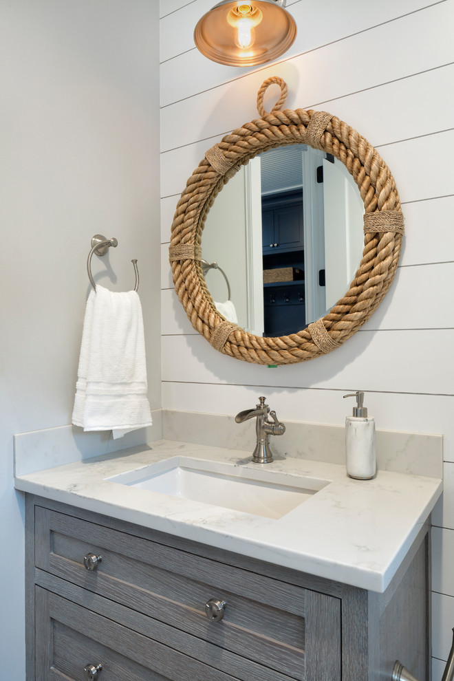 Photo of a beach style powder room in Minneapolis with shaker cabinets, grey cabinets, white walls, an undermount sink and white benchtops.