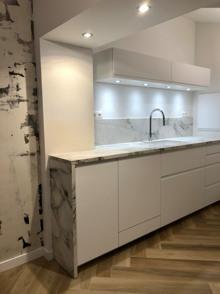 Immagine di una cucina design di medie dimensioni con lavello integrato, ante lisce, ante bianche, top in superficie solida e parquet chiaro