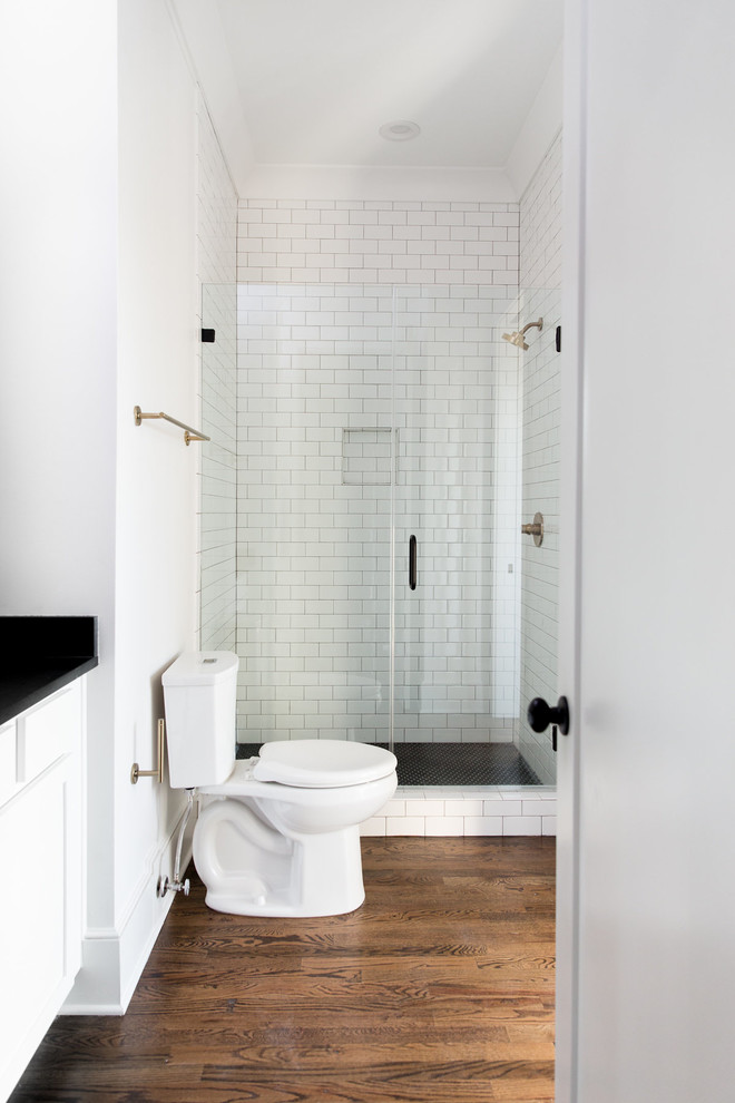 Inspiration for a mid-sized transitional 3/4 bathroom in Charleston with shaker cabinets, white cabinets, an alcove shower, a two-piece toilet, white tile, subway tile, white walls, dark hardwood floors, soapstone benchtops, brown floor and a hinged shower door.