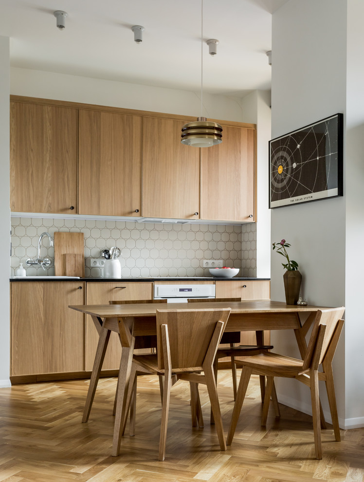 Contemporary single-wall open plan kitchen in Moscow with a drop-in sink, flat-panel cabinets, light wood cabinets, white splashback, white appliances, light hardwood floors, no island and beige floor.