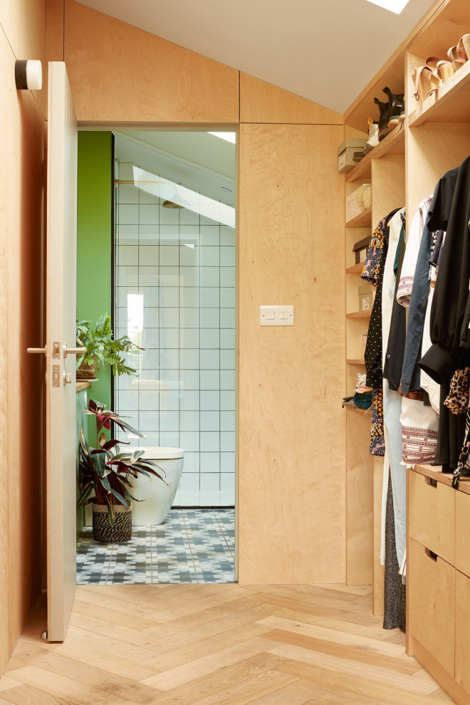 This is an example of a mid-sized scandinavian gender-neutral dressing room in Oxfordshire with flat-panel cabinets, light wood cabinets and light hardwood floors.