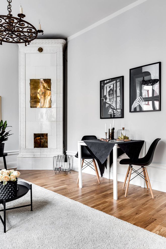 Scandinavian open plan dining in Stockholm with white walls, medium hardwood floors, a wood stove, a tile fireplace surround and brown floor.