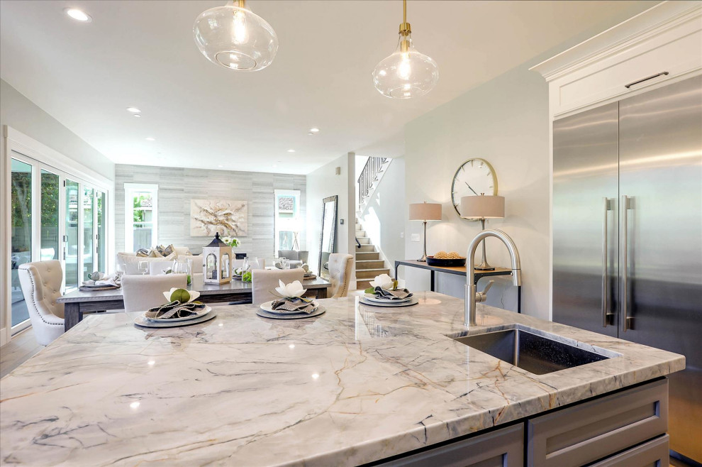 Large beach style u-shaped light wood floor and brown floor open concept kitchen photo in San Francisco with an undermount sink, shaker cabinets, white cabinets, quartzite countertops, white backsplash, ceramic backsplash, an island and blue countertops