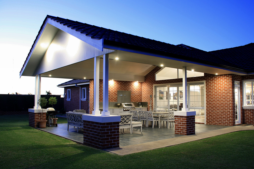 Idee per un grande patio o portico classico dietro casa con piastrelle e un tetto a sbalzo