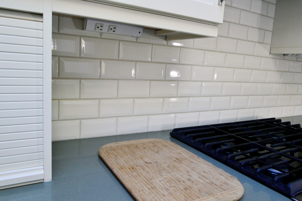 Example of a mid-sized transitional light wood floor enclosed kitchen design in Seattle with an undermount sink, recessed-panel cabinets, white cabinets, quartz countertops, white backsplash, subway tile backsplash, stainless steel appliances and a peninsula