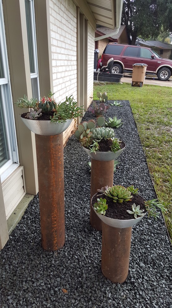 This is an example of a small contemporary front yard full sun xeriscape in Austin with a container garden and gravel.