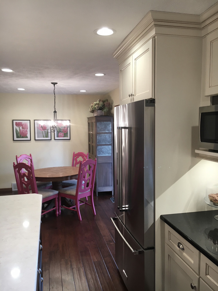Eat-in kitchen - large transitional medium tone wood floor and brown floor eat-in kitchen idea with an undermount sink, flat-panel cabinets, white cabinets, granite countertops, white backsplash, porcelain backsplash, stainless steel appliances and an island