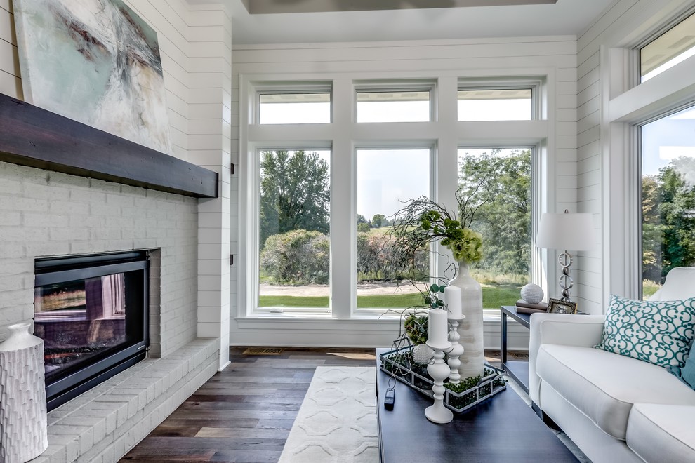 This is an example of an expansive sunroom in Minneapolis with medium hardwood floors, a standard fireplace, a brick fireplace surround and a standard ceiling.