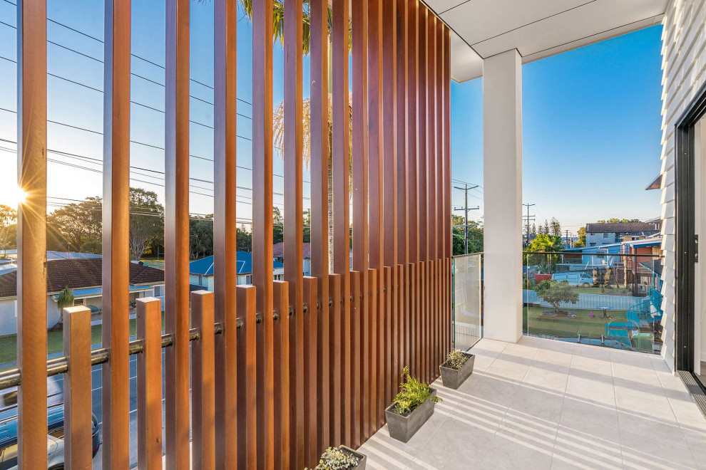 This is an example of a mid-sized contemporary balcony in Gold Coast - Tweed with with privacy feature, a pergola and mixed railing.
