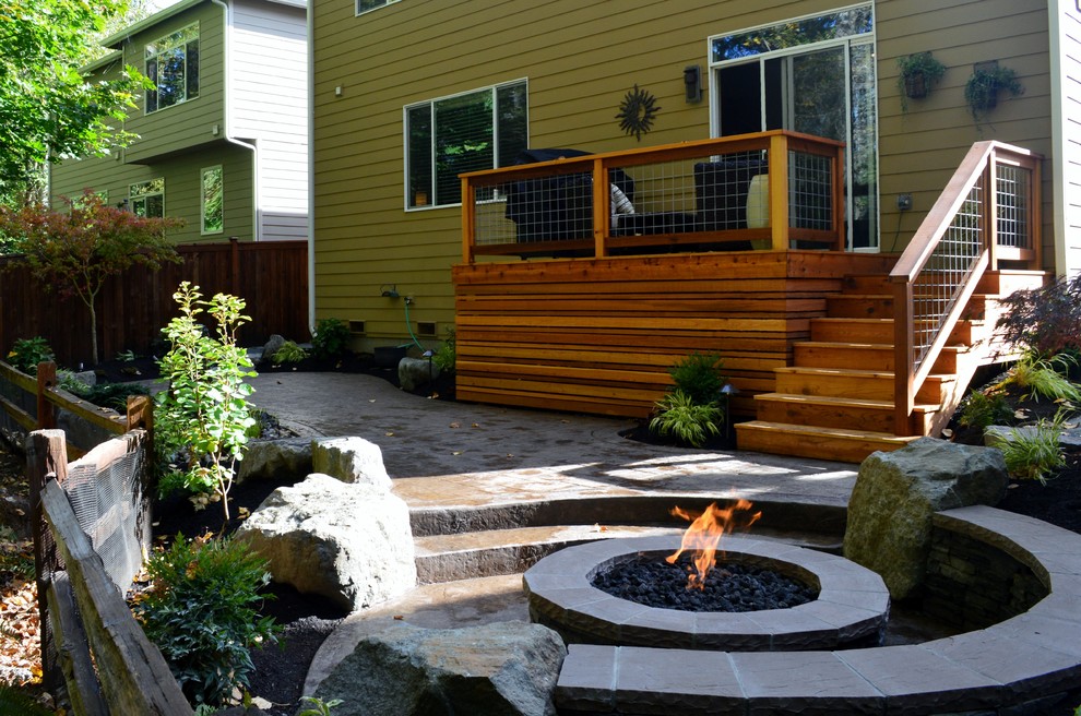 Example of a mid-sized arts and crafts backyard stamped concrete patio design in Seattle with a fire pit and no cover