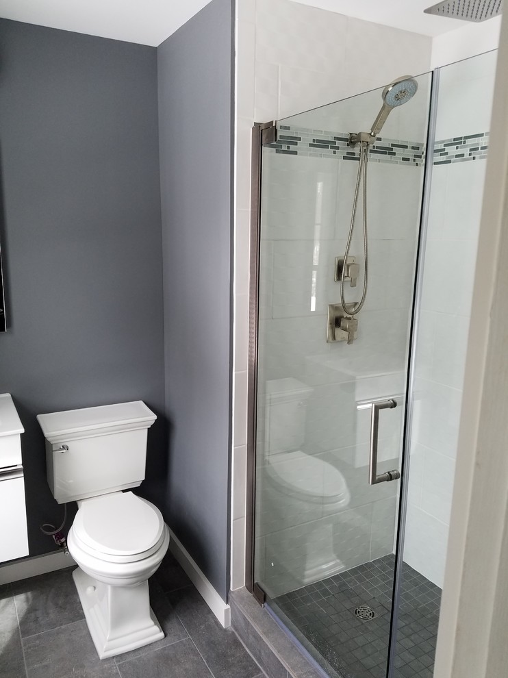 Design ideas for a small contemporary master bathroom in New York with flat-panel cabinets, white cabinets, an alcove shower, a two-piece toilet, white tile, grey walls, grey floor and a hinged shower door.