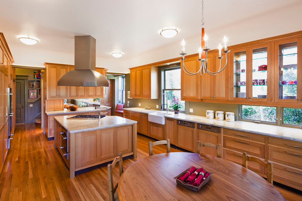 This is an example of a traditional u-shaped eat-in kitchen in San Francisco with a farmhouse sink, recessed-panel cabinets, medium wood cabinets, granite benchtops, medium hardwood floors, with island and panelled appliances.