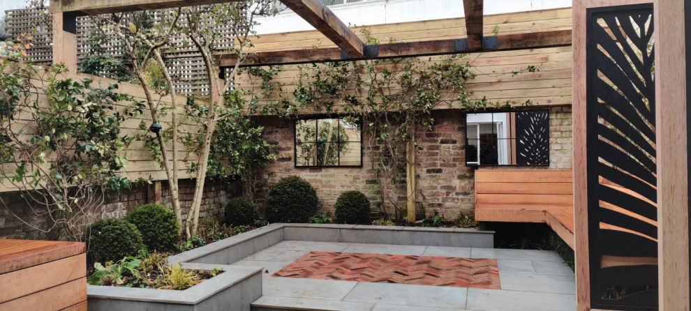 Aménagement d'un petit jardin avec pergola arrière industriel l'été avec une exposition partiellement ombragée et des pavés en brique.