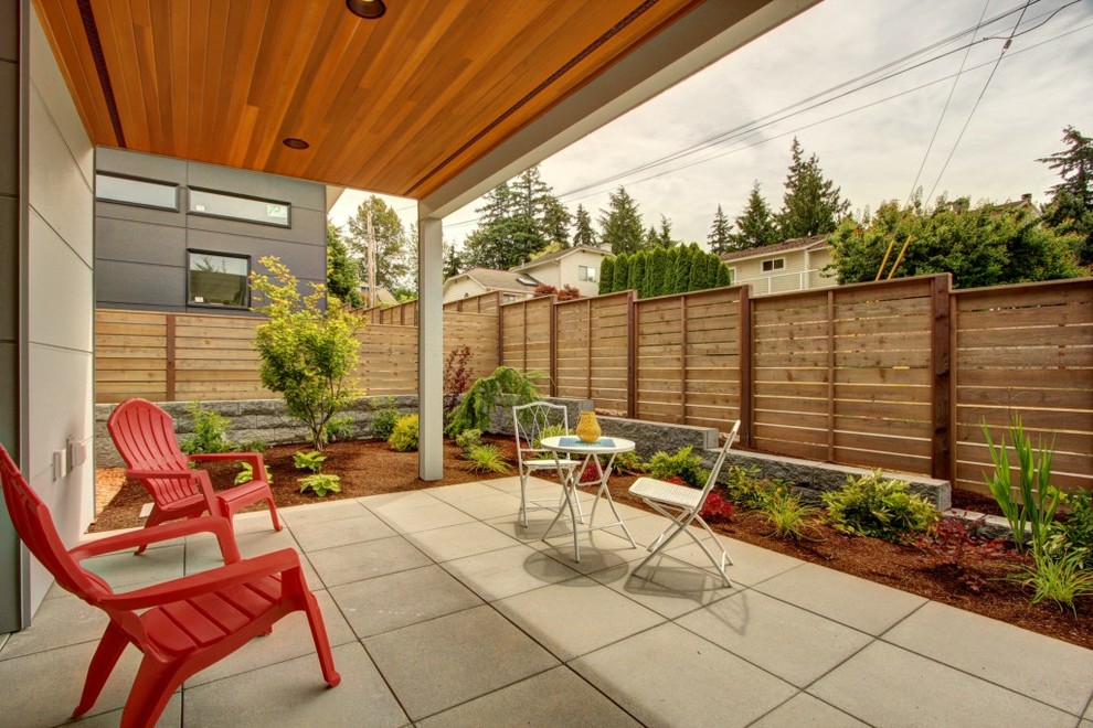 Design ideas for a modern backyard patio in Seattle with concrete pavers and a roof extension.