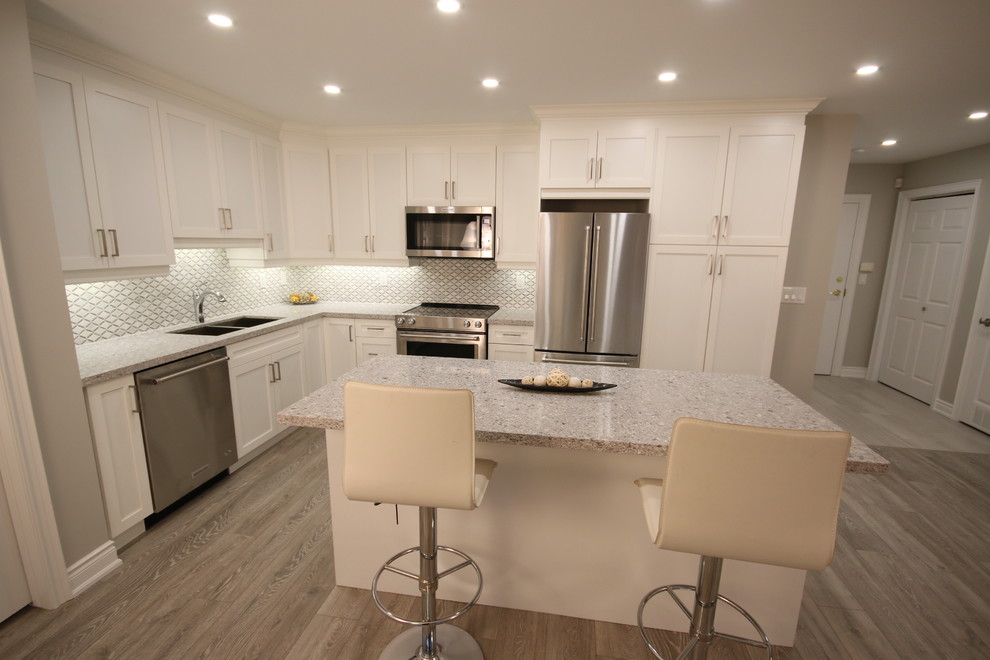 This is an example of a mid-sized contemporary l-shaped kitchen in Toronto with an undermount sink, shaker cabinets, white cabinets, quartz benchtops, yellow splashback, stainless steel appliances and with island.