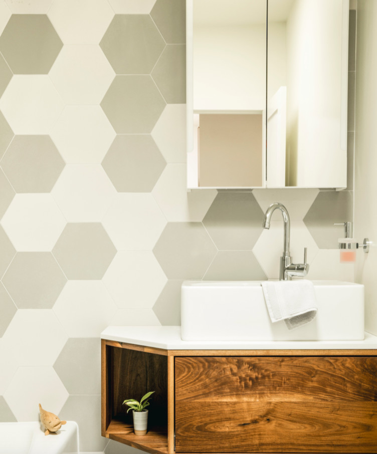 Inspiration for a small contemporary 3/4 beige tile, white tile and ceramic tile corner bathtub remodel in Orange County with flat-panel cabinets, medium tone wood cabinets, beige walls, a vessel sink and solid surface countertops