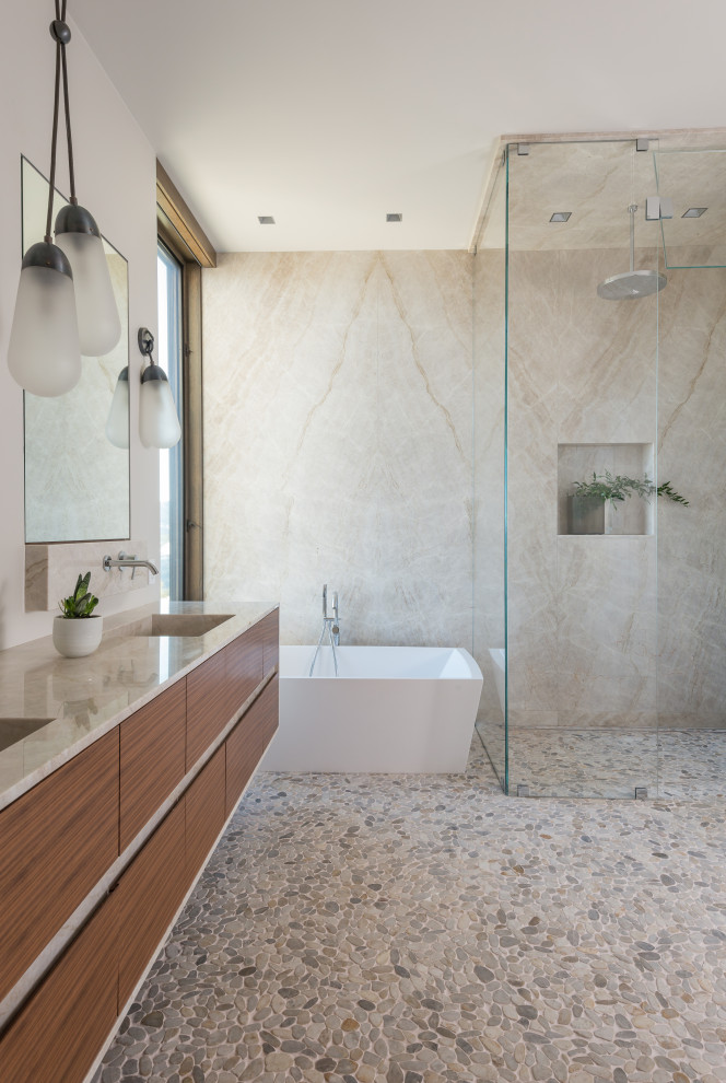Country master bathroom in Other with flat-panel cabinets, medium wood cabinets, a freestanding tub, a curbless shower, beige tile, stone slab, white walls, pebble tile floors, an integrated sink, multi-coloured floor, beige benchtops, a double vanity and a floating vanity.
