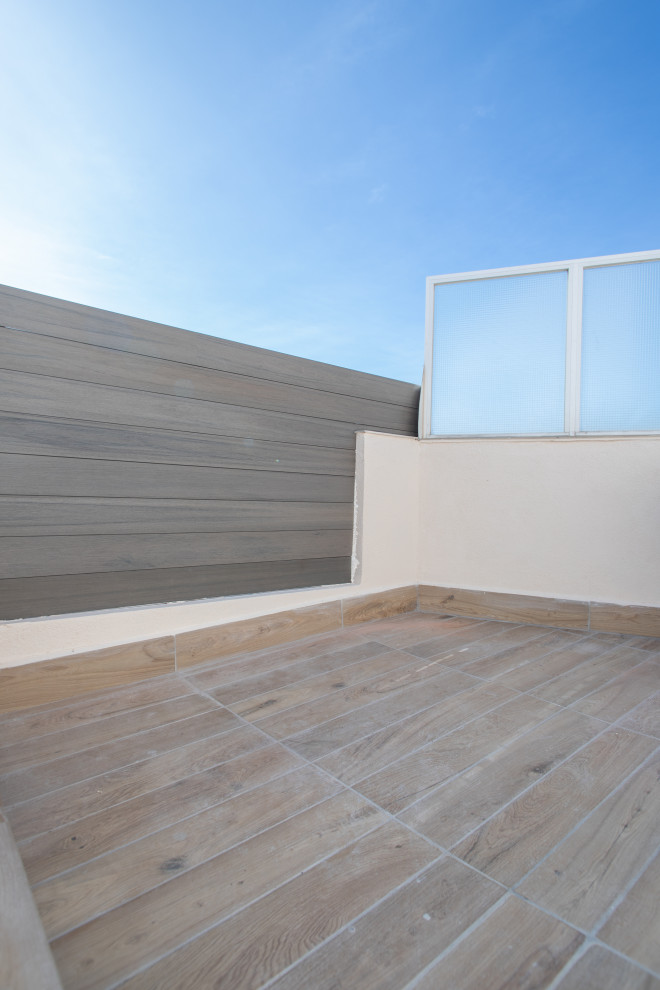 This is an example of a large mediterranean roof rooftop wood railing terrace in Barcelona with skirting and no cover.