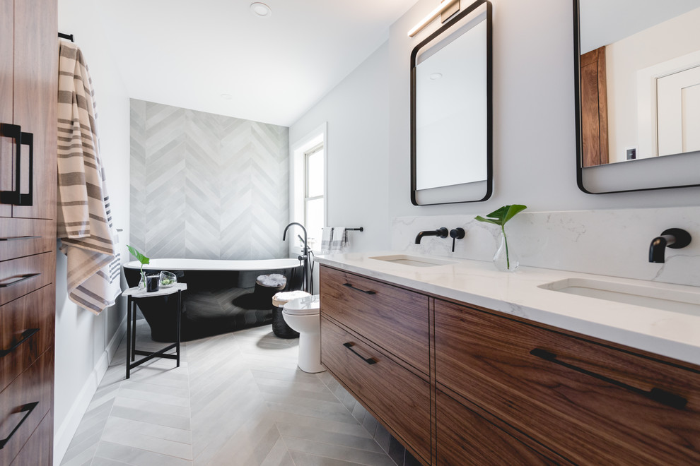 Photo of a mid-sized contemporary master bathroom in Montreal with flat-panel cabinets, dark wood cabinets, a freestanding tub, an alcove shower, a one-piece toilet, gray tile, porcelain tile, grey walls, porcelain floors, an undermount sink, quartzite benchtops, grey floor, an open shower and white benchtops.