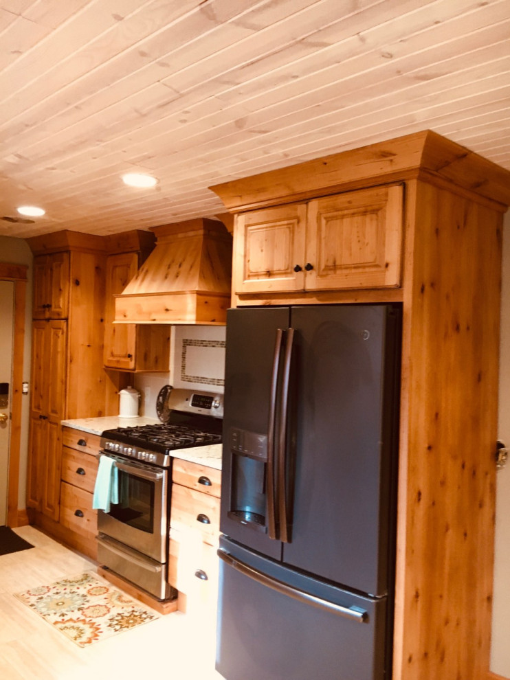 Enclosed kitchen - mid-sized rustic u-shaped enclosed kitchen idea with a farmhouse sink, raised-panel cabinets, light wood cabinets, quartz countertops, beige backsplash, limestone backsplash, stainless steel appliances and no island