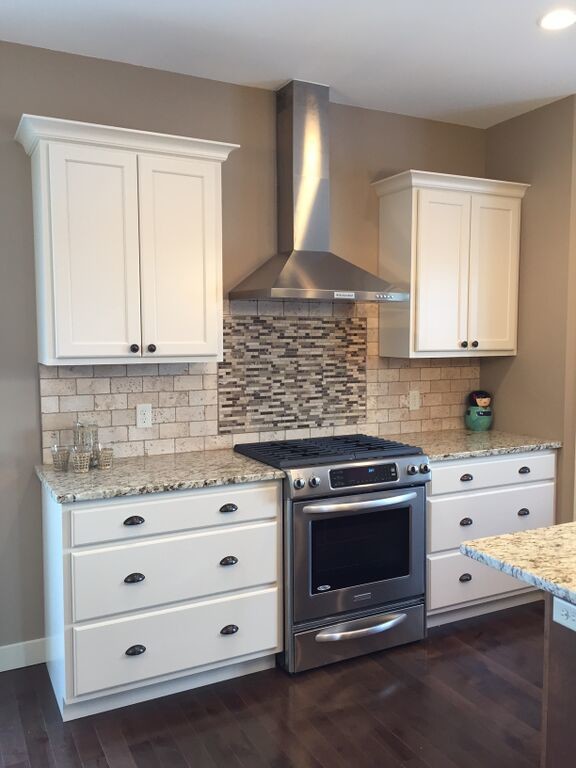 Mid-sized transitional dark wood floor kitchen photo with recessed-panel cabinets, white cabinets, granite countertops, beige backsplash, stone tile backsplash and stainless steel appliances