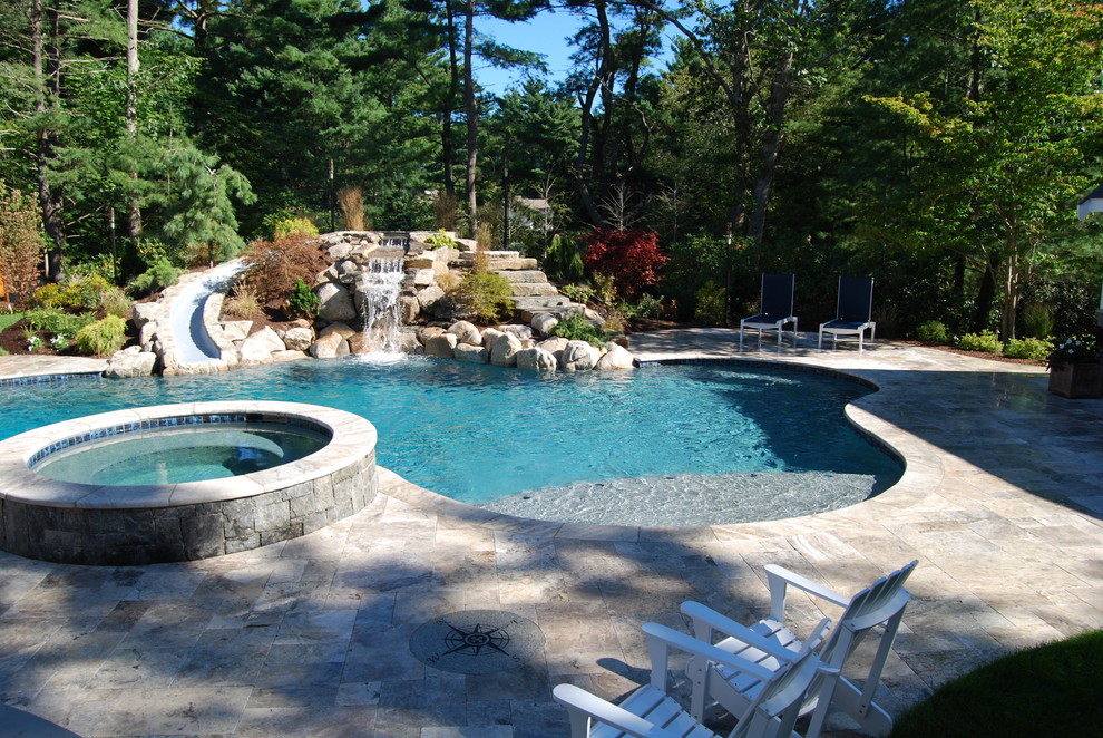 This is an example of a mid-sized country backyard kidney-shaped natural pool in Boston with a water slide and natural stone pavers.