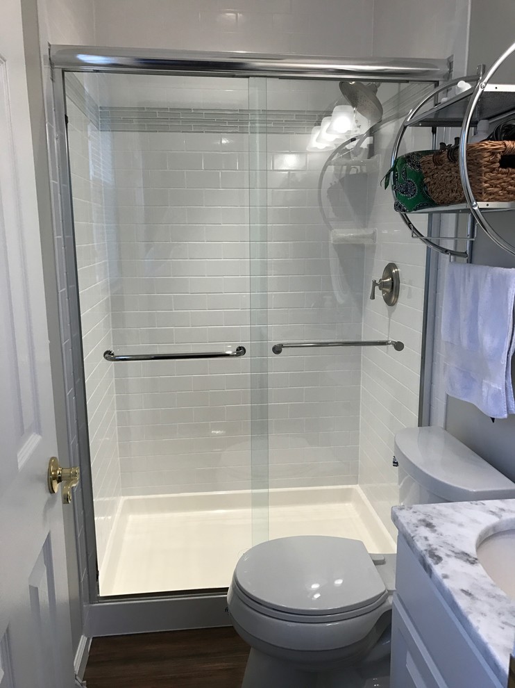 Small contemporary 3/4 bathroom in DC Metro with white tile, ceramic tile, porcelain floors, raised-panel cabinets, white cabinets, an alcove shower, a two-piece toilet, grey walls, an undermount sink, marble benchtops, brown floor and a sliding shower screen.