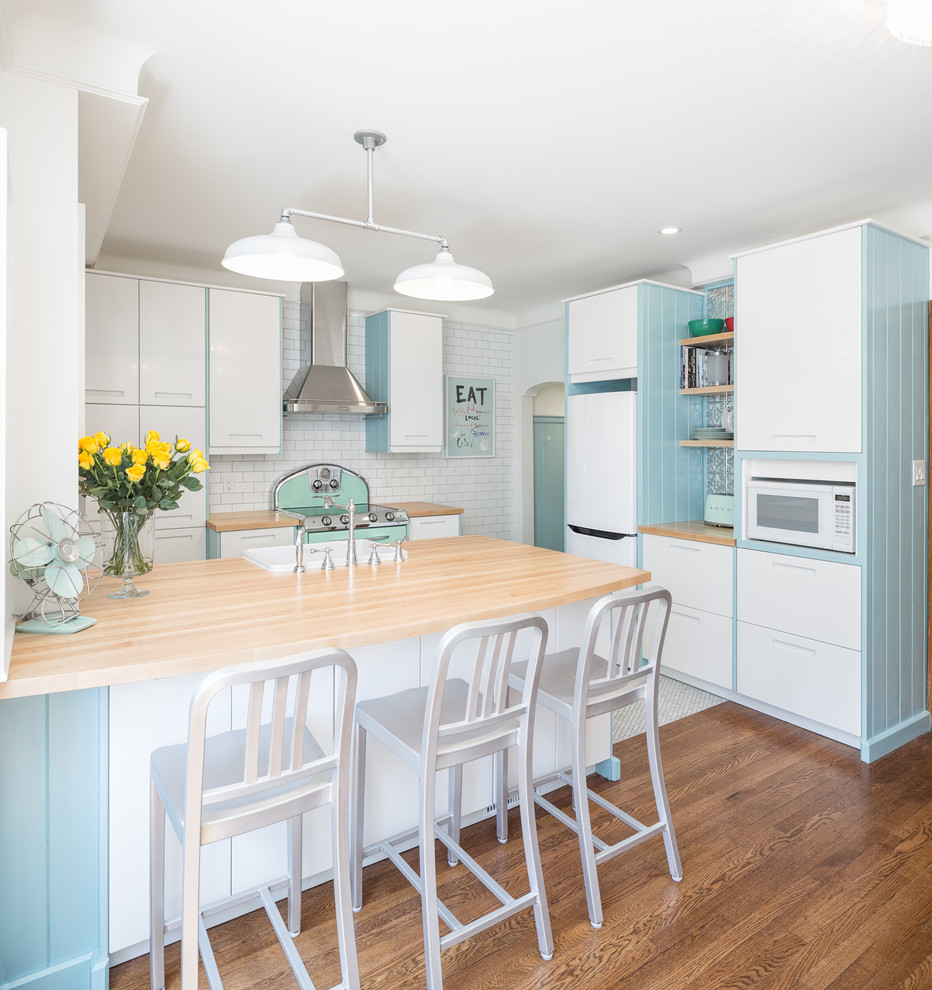 Inspiration for a small transitional l-shaped marble floor eat-in kitchen remodel in Ottawa with a farmhouse sink, flat-panel cabinets, white cabinets, wood countertops, white backsplash, subway tile backsplash, colored appliances and a peninsula