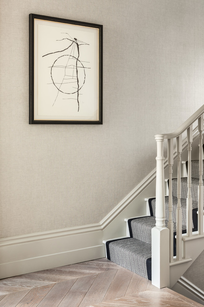 Design ideas for a mid-sized traditional carpeted staircase in London with carpet risers and wood railing.
