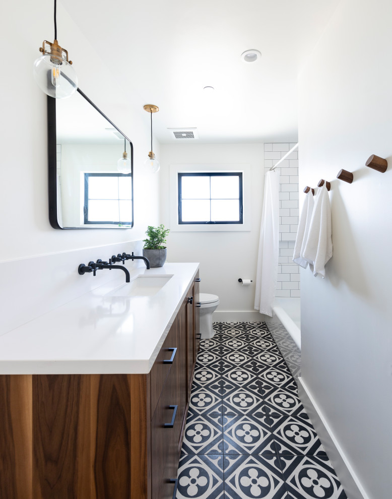 This is an example of a country bathroom in San Francisco with flat-panel cabinets, medium wood cabinets, an alcove shower, white tile, subway tile, white walls, an undermount sink, multi-coloured floor, a shower curtain, white benchtops, a single vanity and a built-in vanity.