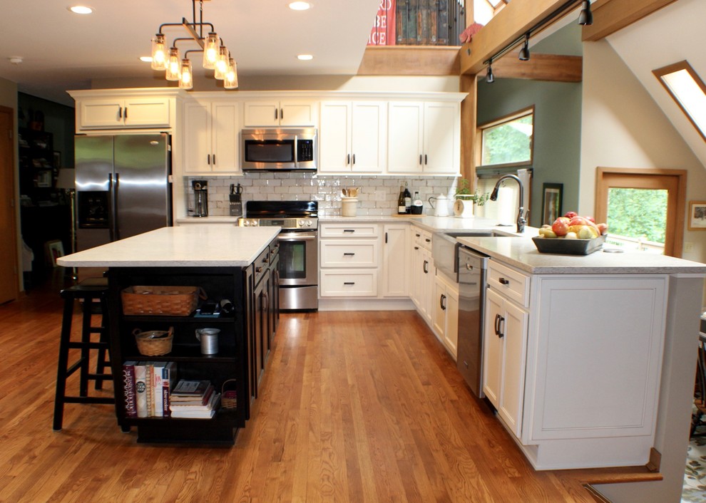 Example of a mid-sized mountain style u-shaped medium tone wood floor and brown floor eat-in kitchen design in Cincinnati with a farmhouse sink, shaker cabinets, white cabinets, quartz countertops, white backsplash, subway tile backsplash, stainless steel appliances, an island and white countertops
