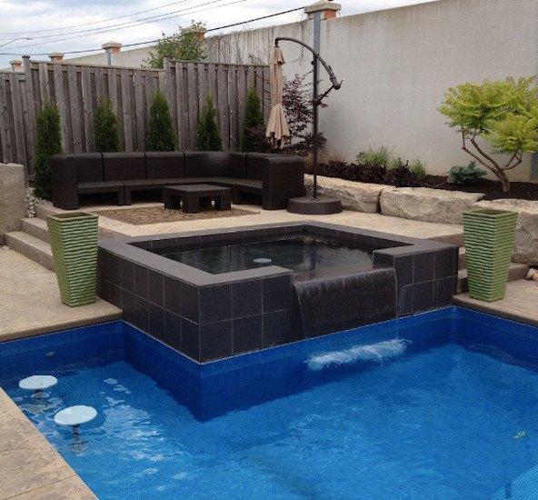 This is an example of a small modern backyard custom-shaped natural pool in Toronto with a hot tub and stamped concrete.
