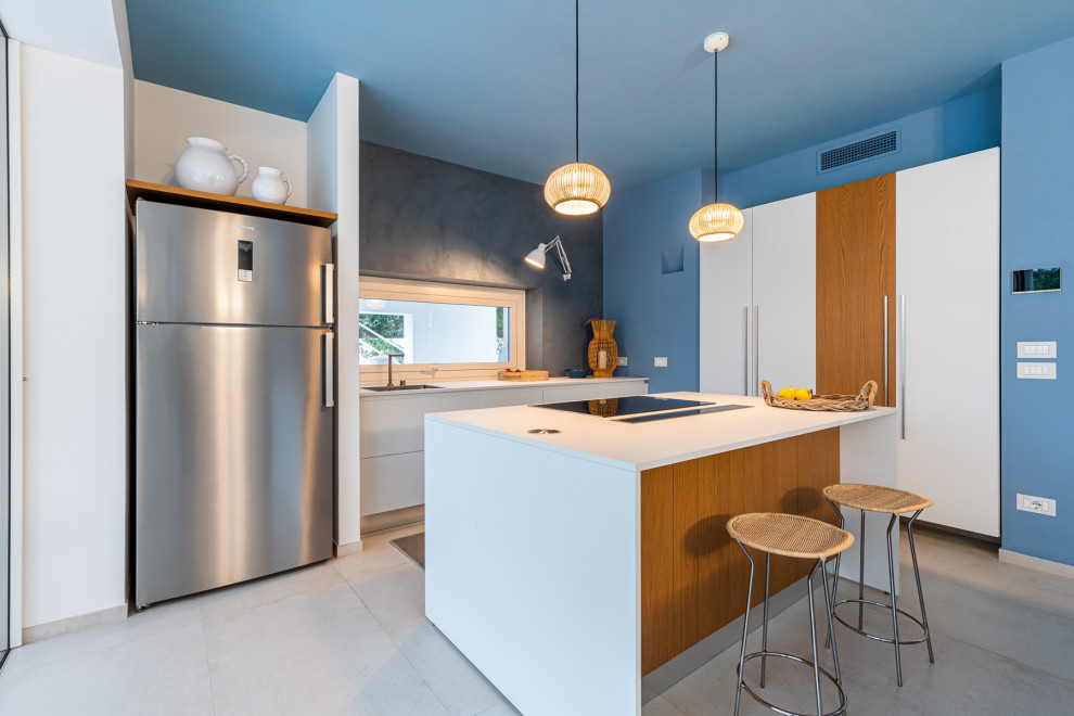 Photo of a coastal kitchen in Bari with a single-bowl sink, flat-panel cabinets, stainless steel appliances, concrete flooring, an island, grey floors and white worktops.