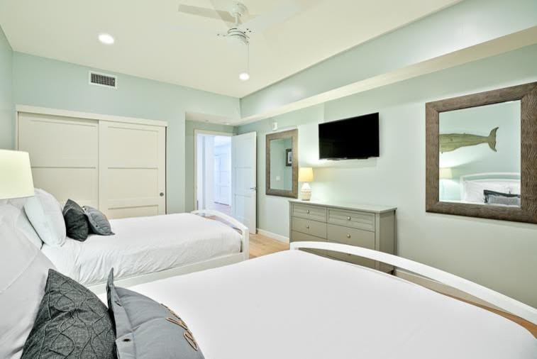 Design ideas for a mid-sized beach style guest bedroom in San Diego with green walls and light hardwood floors.