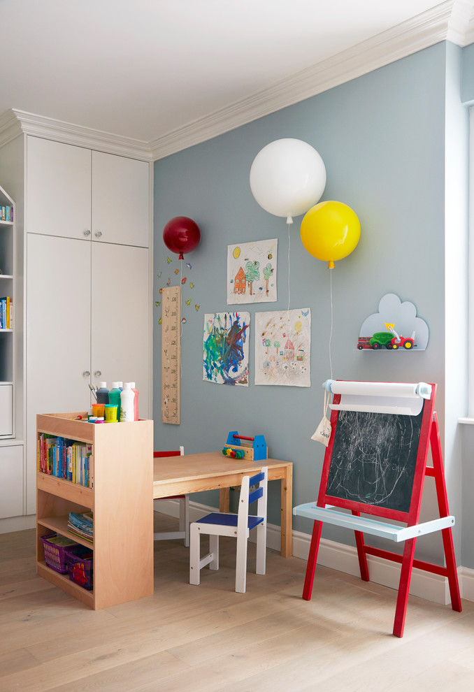 Large contemporary gender-neutral kids' room in London with blue walls, light hardwood floors and beige floor.
