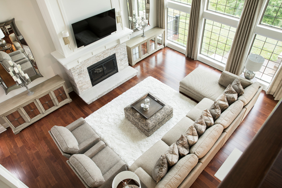 Inspiration for a large transitional formal open concept living room in Milwaukee with grey walls, medium hardwood floors, a standard fireplace, a stone fireplace surround, brown floor and a freestanding tv.