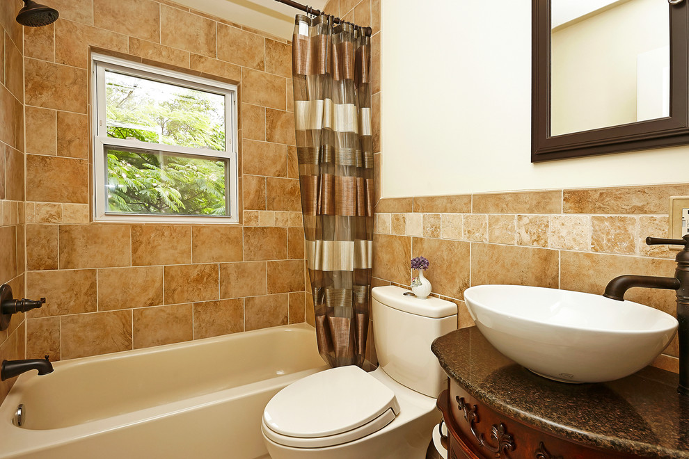 Photo of a mid-sized traditional 3/4 bathroom in DC Metro with medium wood cabinets, an alcove tub, a shower/bathtub combo, a one-piece toilet, brown tile, white walls, a vessel sink, ceramic floors, furniture-like cabinets and stone tile.