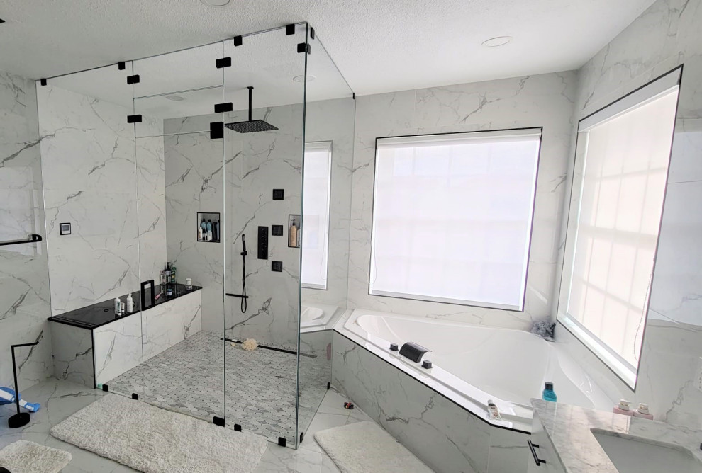 Foto de cuarto de baño grande con bañera esquinera, sanitario de dos piezas, baldosas y/o azulejos blancas y negros y suelo blanco