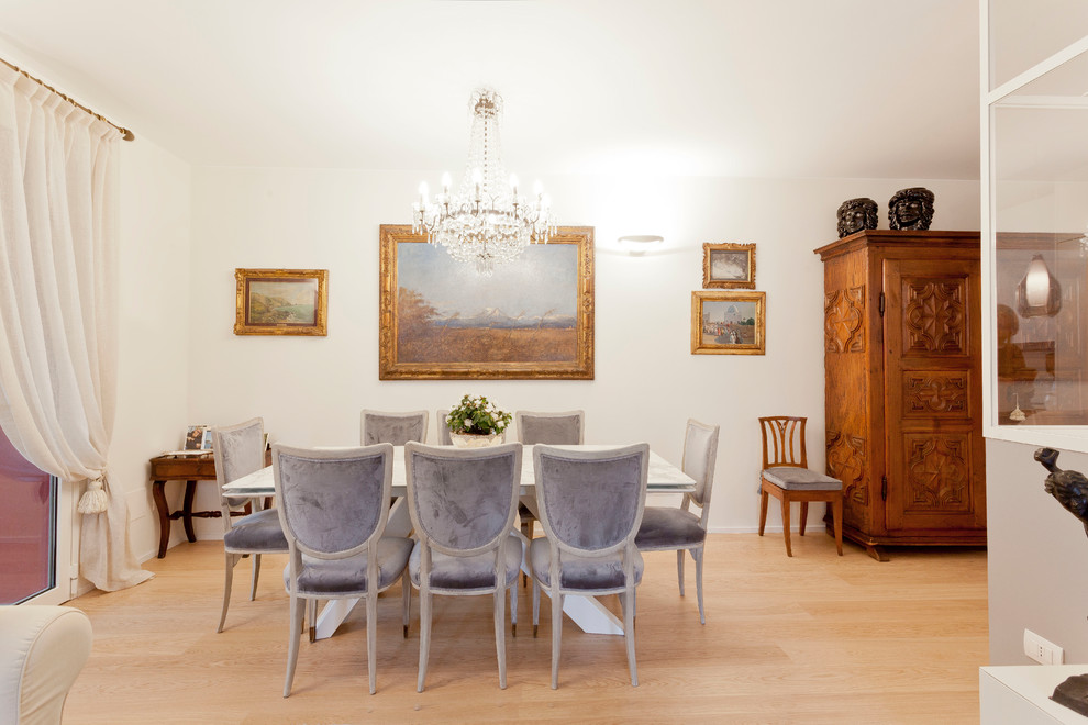 This is an example of a large traditional dining room in Milan with light hardwood floors, beige floor and white walls.