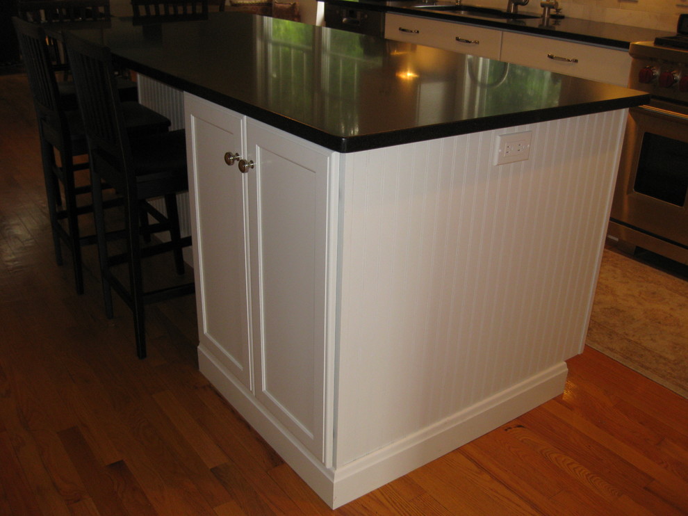 Inspiration for a transitional u-shaped medium tone wood floor eat-in kitchen remodel in Boston with an undermount sink, recessed-panel cabinets, white cabinets, gray backsplash, subway tile backsplash, stainless steel appliances, an island and black countertops