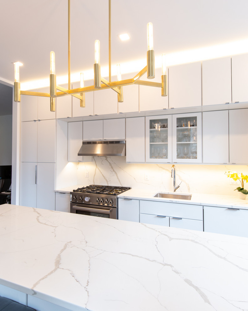 Design ideas for a mid-sized modern galley separate kitchen in New York with an undermount sink, flat-panel cabinets, white cabinets, quartz benchtops, white splashback, engineered quartz splashback, panelled appliances, light hardwood floors, with island, brown floor and white benchtop.