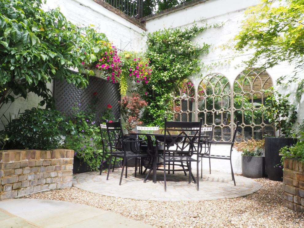 Design ideas for a small traditional courtyard partial sun formal garden for summer in London with with raised garden bed and natural stone pavers.