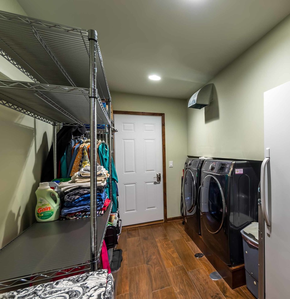 Mid-sized country galley utility room in Chicago with open cabinets, stainless steel cabinets, yellow walls, ceramic floors, a side-by-side washer and dryer, brown floor, wallpaper and wallpaper.