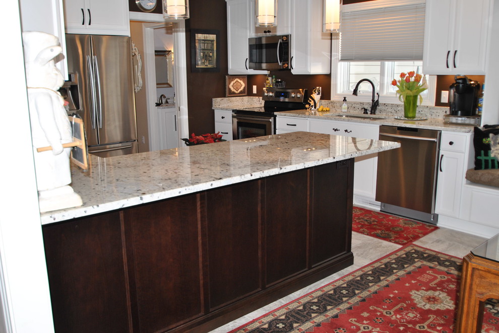 This is an example of a mid-sized u-shaped eat-in kitchen in Minneapolis with an undermount sink, flat-panel cabinets, white cabinets, granite benchtops, stainless steel appliances, vinyl floors and no island.