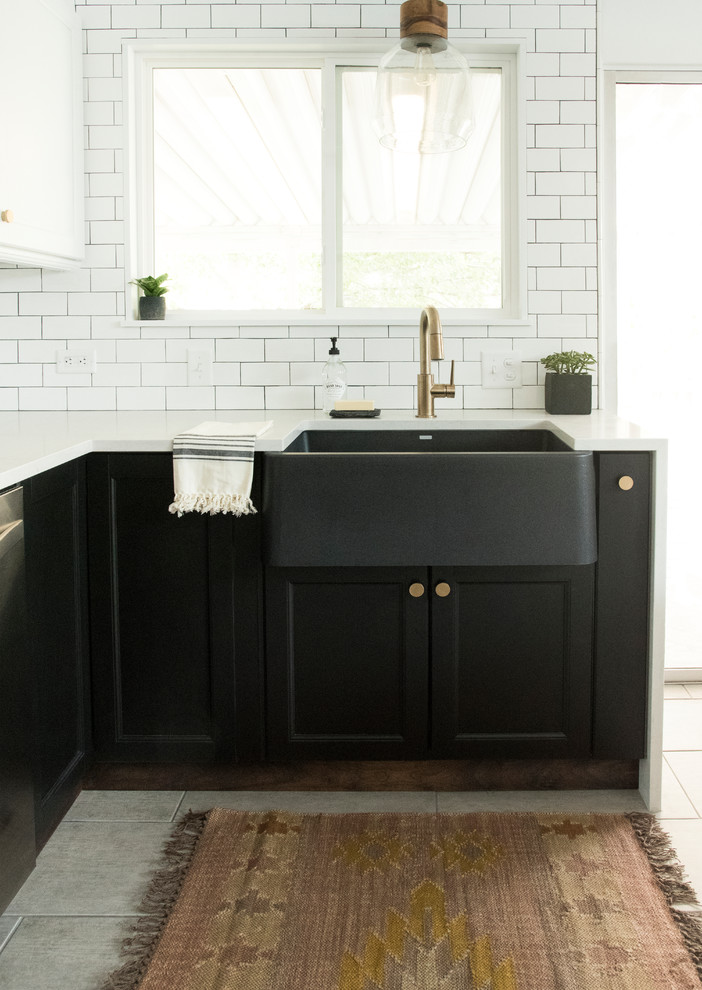 Inspiration for a mid-sized country u-shaped eat-in kitchen in Salt Lake City with a farmhouse sink, white splashback, subway tile splashback, stainless steel appliances, porcelain floors, no island, grey floor, shaker cabinets, black cabinets, quartz benchtops and white benchtop.