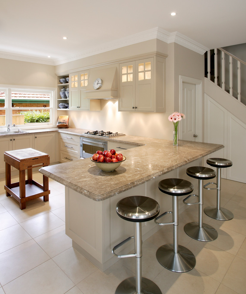 Design ideas for a transitional u-shaped kitchen in Sydney with a drop-in sink, shaker cabinets, beige cabinets, granite benchtops, beige splashback, stainless steel appliances, ceramic floors, a peninsula and beige benchtop.
