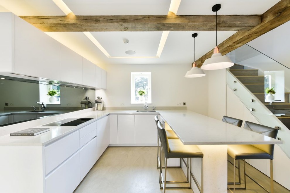 Inspiration for a mid-sized contemporary u-shaped open plan kitchen in London with flat-panel cabinets, grey cabinets, quartz benchtops, stainless steel appliances, concrete floors, with island, beige floor, an undermount sink, black splashback, mirror splashback and grey benchtop.