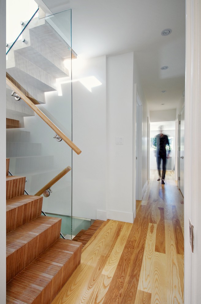 Photo of a mid-sized contemporary hallway in Toronto with white walls, light hardwood floors and brown floor.